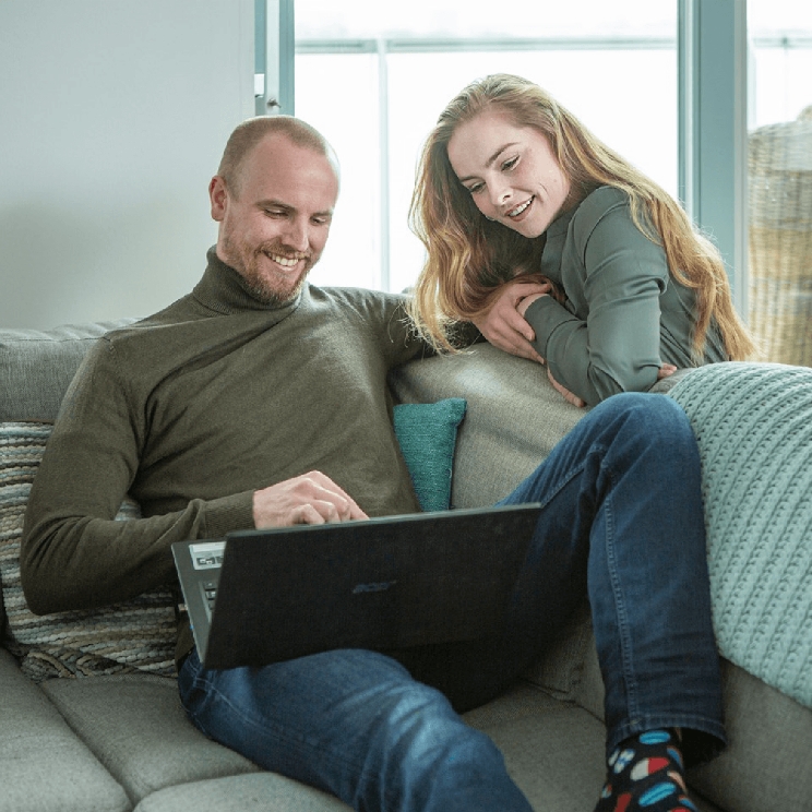 Twee mensen die met de computer op de bank hangen